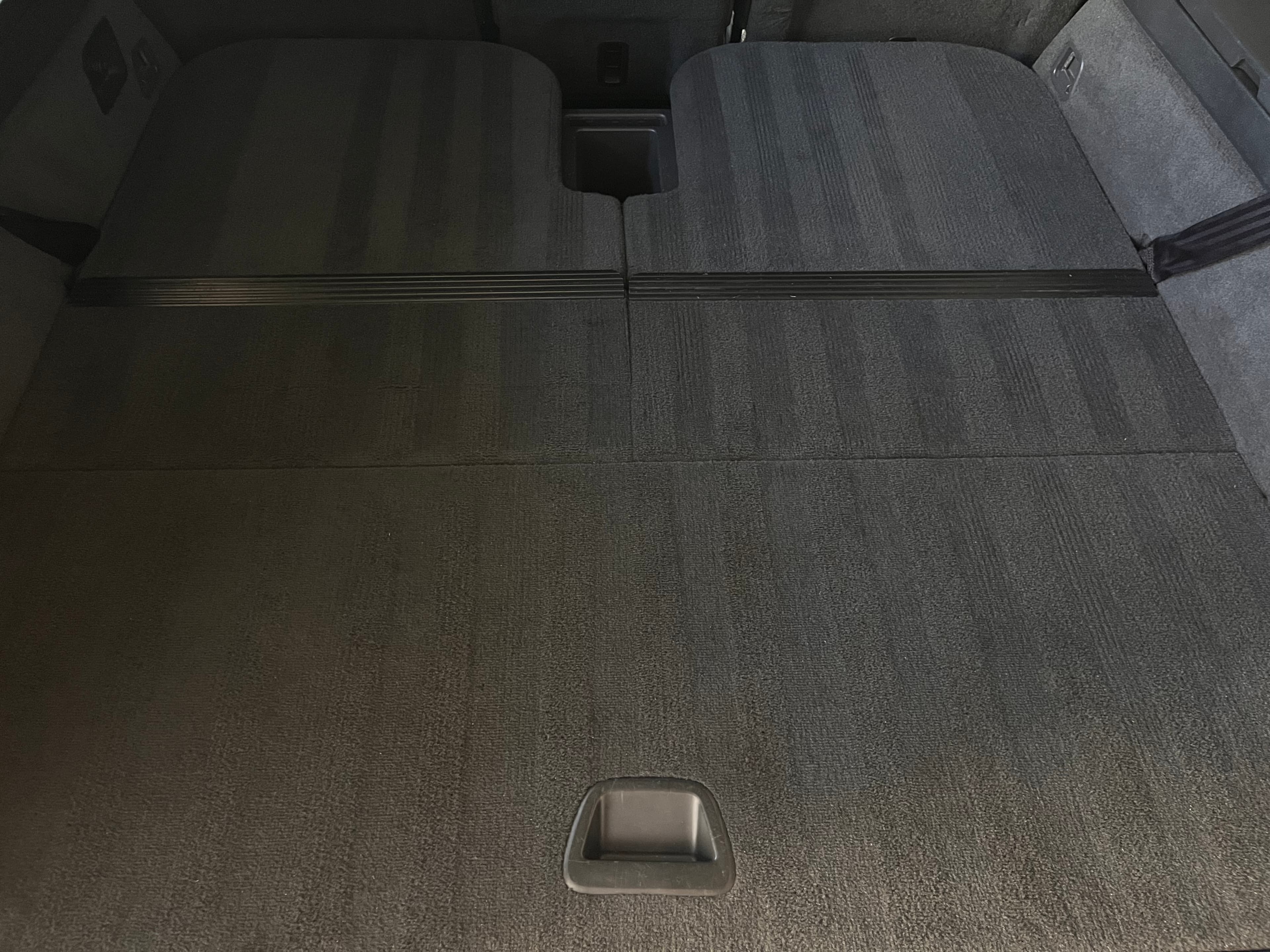 Spacious dark gray carpeted cargo area of a vehicle with rear seats folded completely flat.