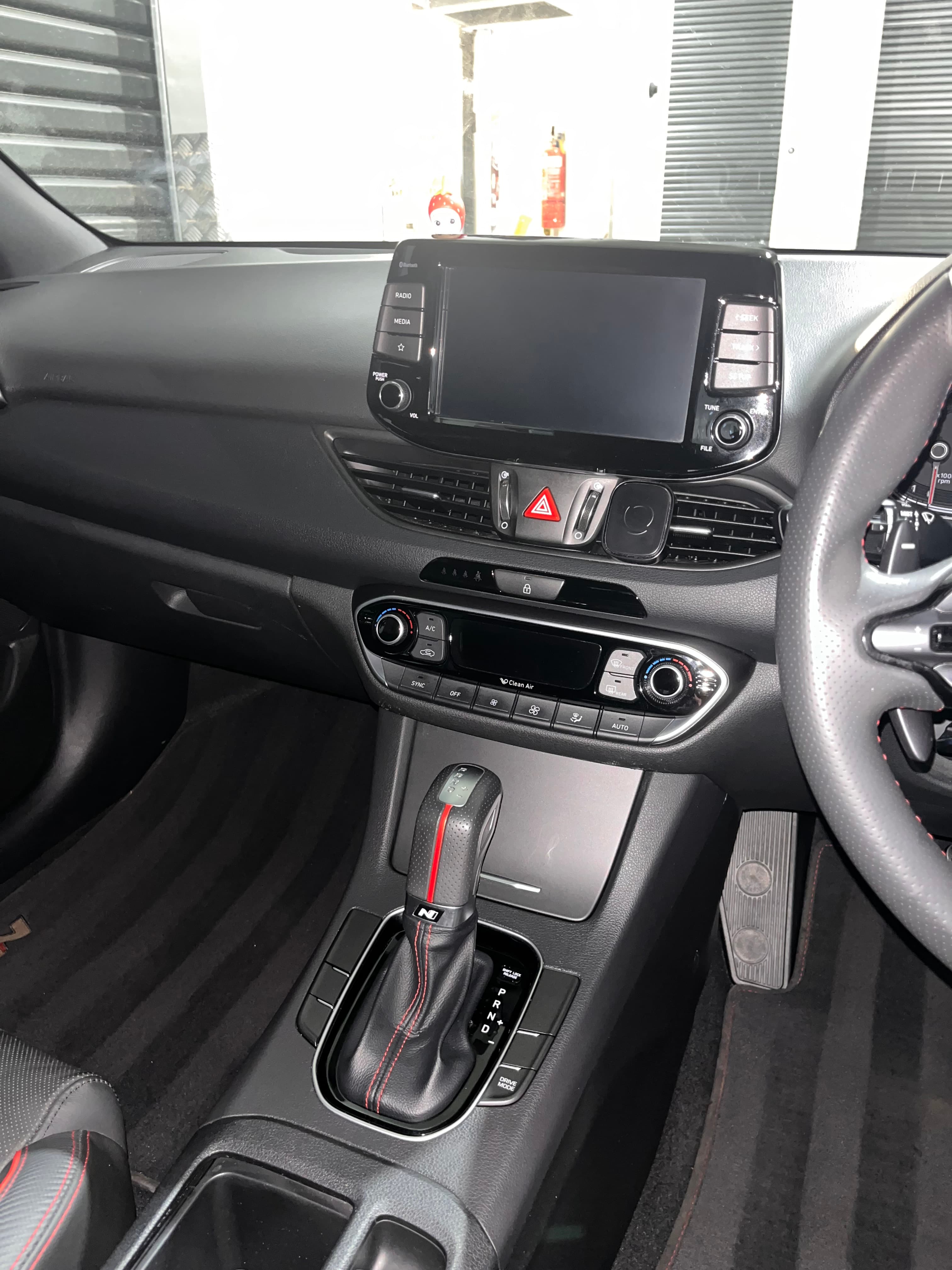 Modern car interior showing the dashboard, touchscreen, climate controls, and leather gear shift lever.